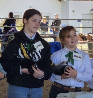 Two girls presenting their rabbits.