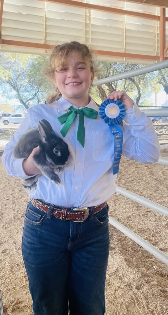 Girl showing winning ribbon award and rabbit.